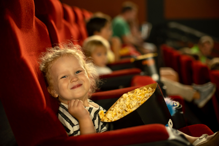 Jente kosar seg med popkorn på kino.
