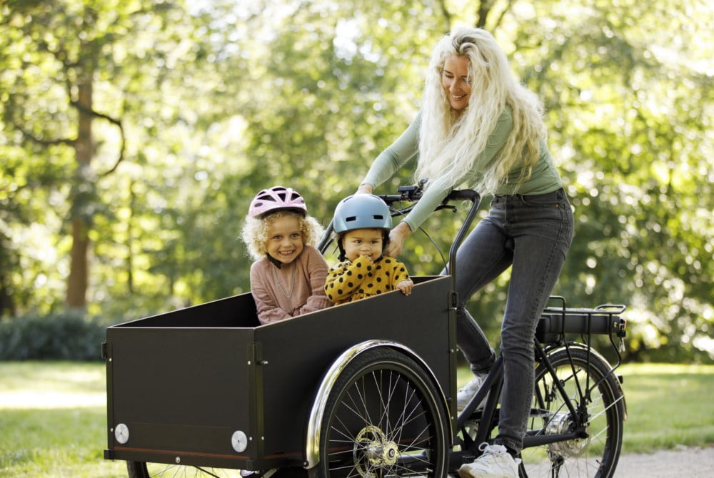 Dame sykler med to barn