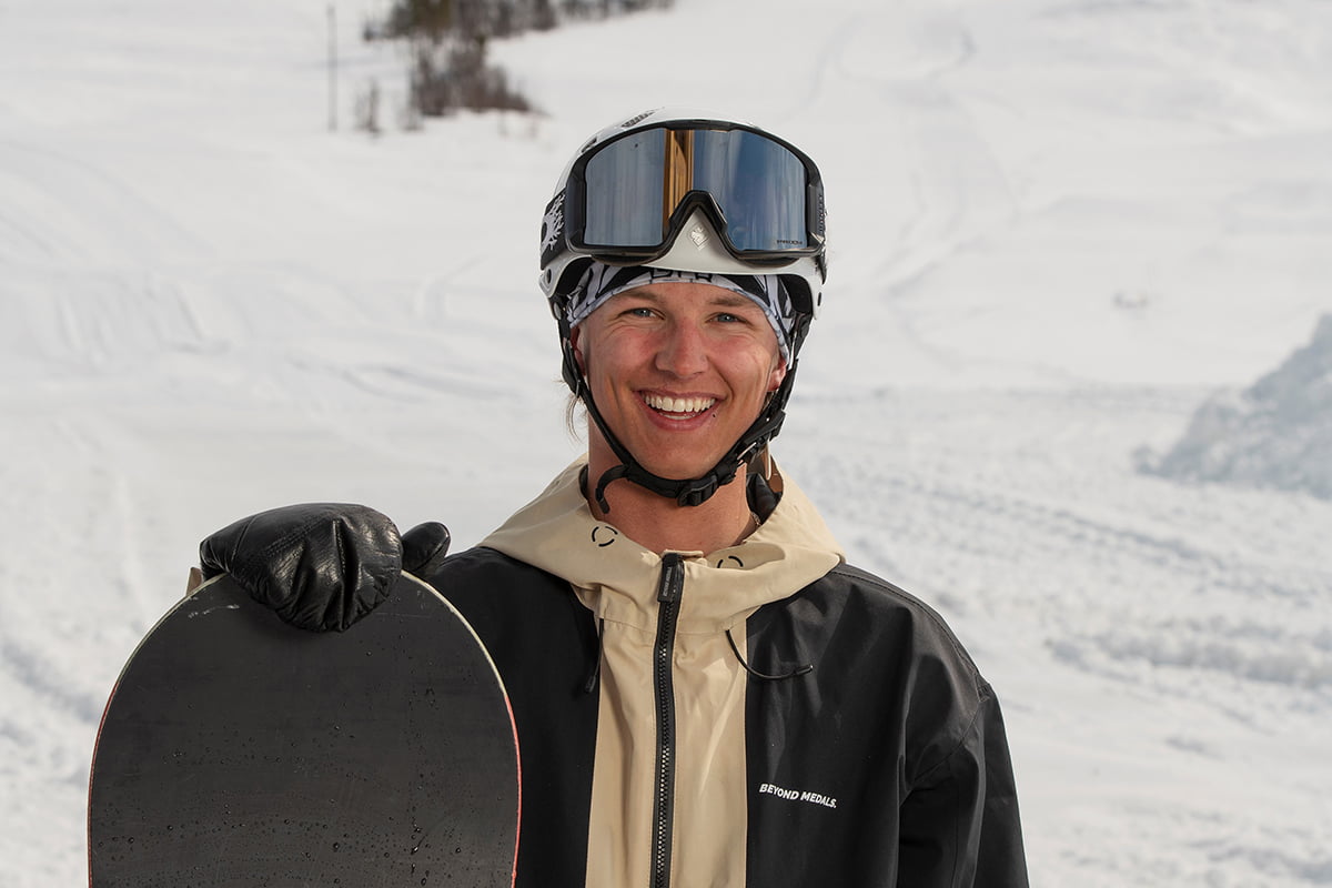 gutt med snowboard foran skibakke